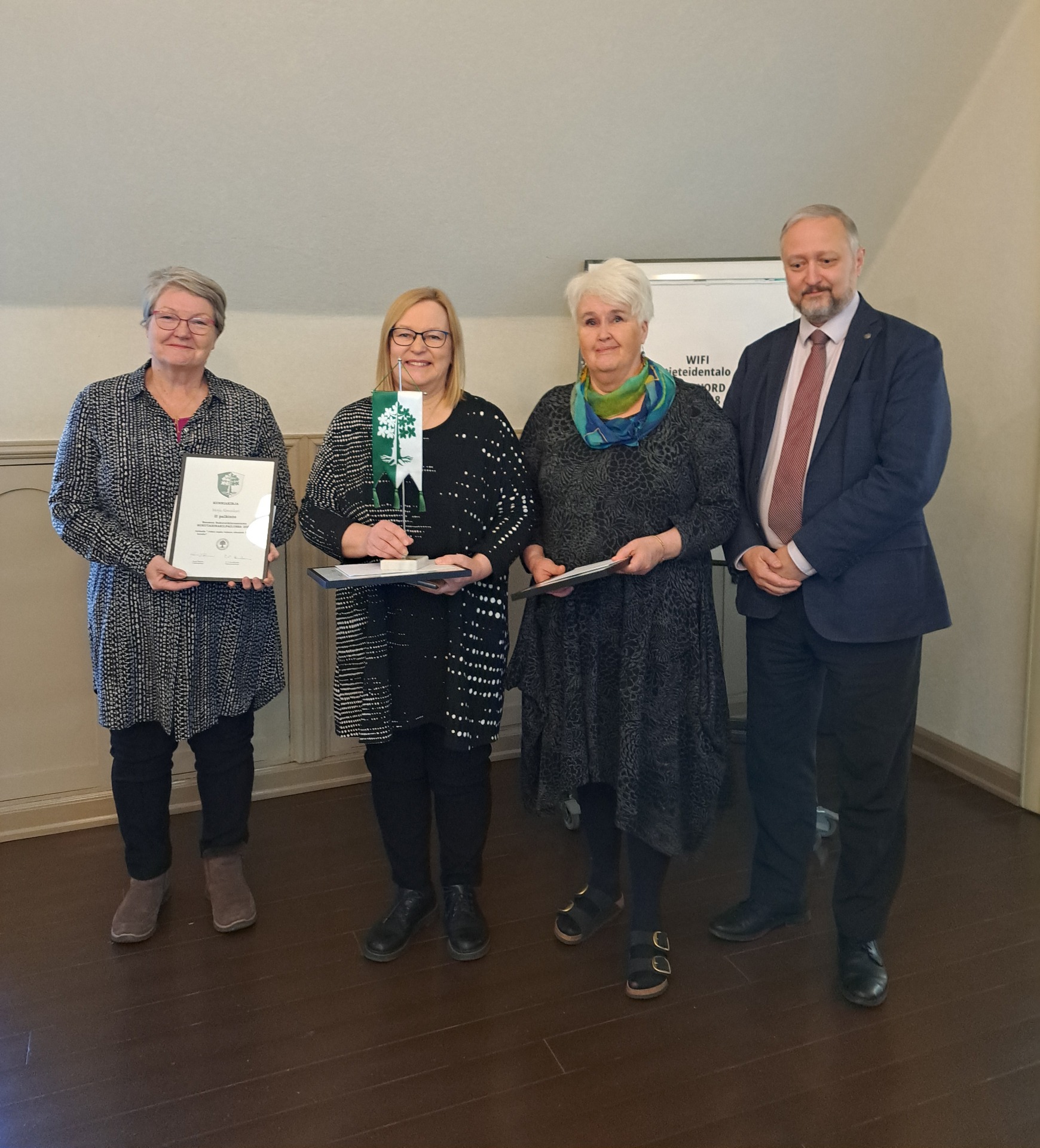 Andra platsen vinnare Merja Almonkari, tävlingens vinnare Ulla Parviainen, och tredje plats tilldelades Eliina Saarinen samt Samfundets ordförande Jouni Elomaa. Foto Maarit Toivonen.